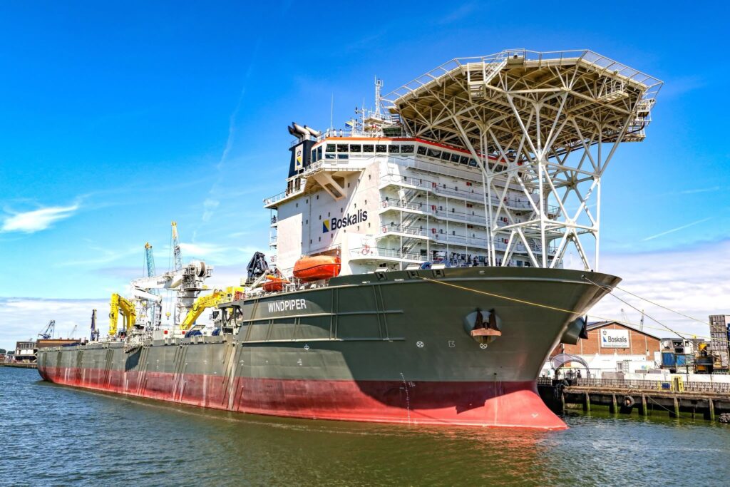 The Boskalis subsea rock installation vessel Windpiper berthed alongside a quay, showing its large cargo capacity and distinctive elevated fall-pipe installation structure above the bow