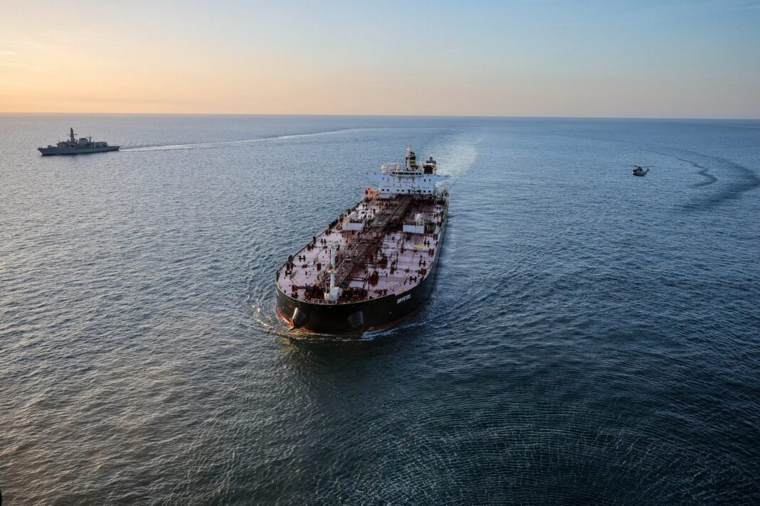 Europe Targets Shadow Fleet Tankers Falsely Flying Cameroon Flag, Sources Say Aerial view of the tanker Smyrtos underway at sea, flanked at a distance by a Royal Navy warship and a helicopter following a UK enforcement operation in the English Channel.