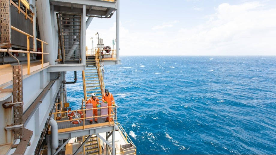 ExxonMobil passes the baton for Australian oil & gas asset to Woodside Two workers on an offshore platform